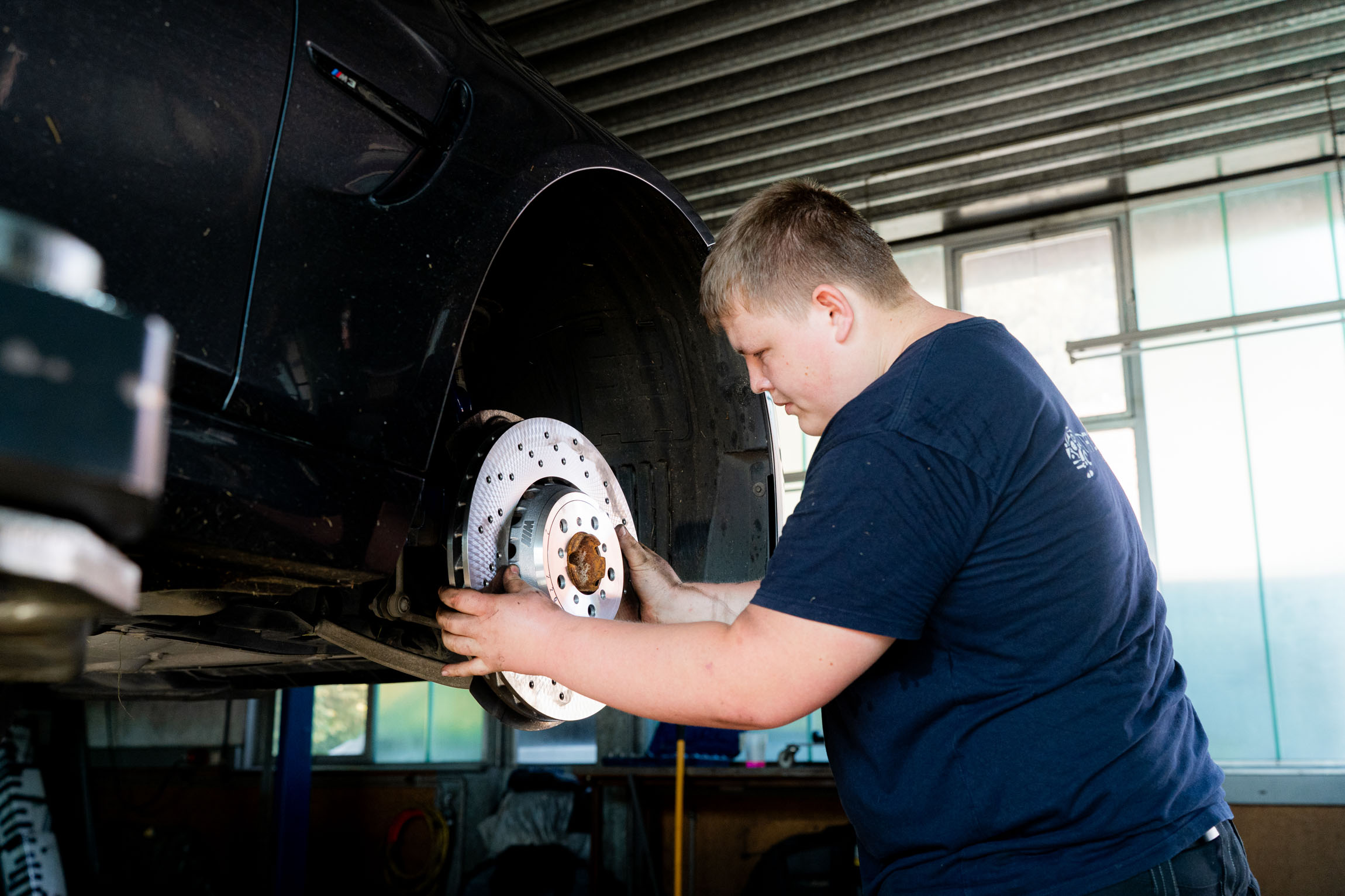 Ein Mann arbeitet an einem Auto in einer Garage, um Reparaturen durchzuführen und die Leistung zu verbessern.