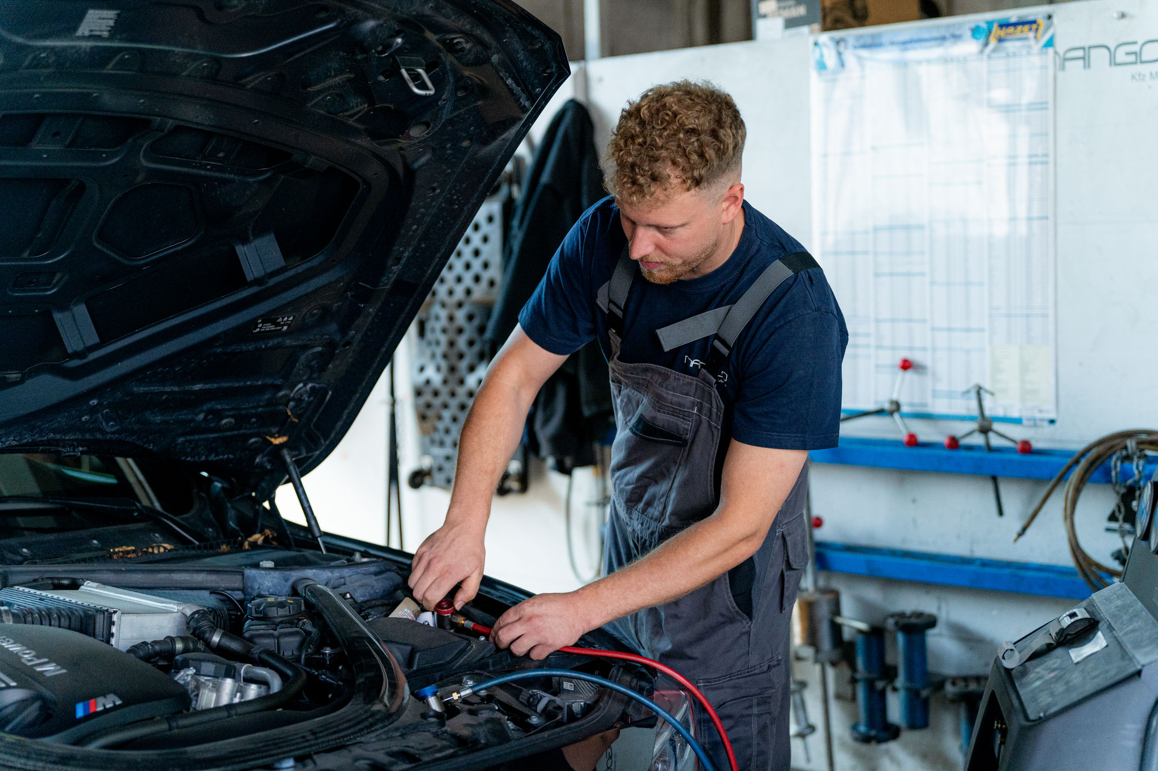 In einer Garage führt ein Mann Wartungsarbeiten an einem Auto durch, um dessen Funktionalität sicherzustellen.