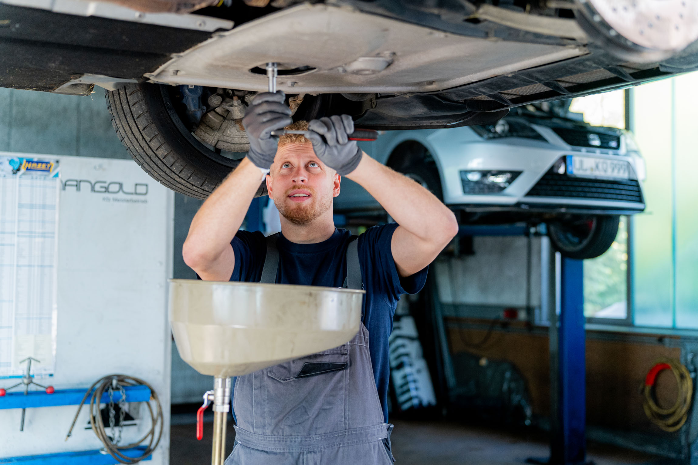 Ein Mann führt einen Ölservice durch, während er unter einem Auto arbeitet.