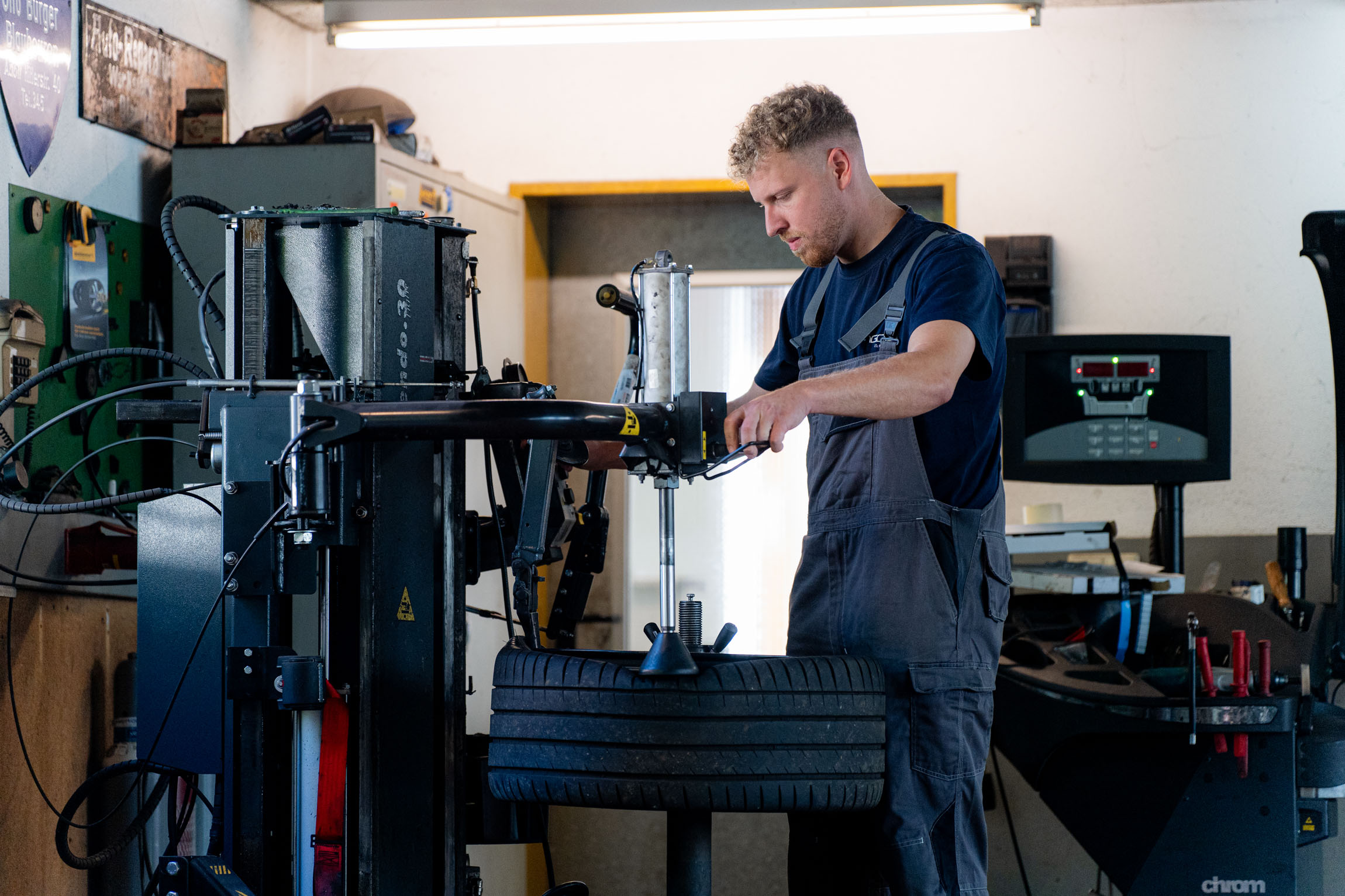 Ein Mann arbeitet an einer Reifenmaschine in einer Werkstatt, um Reifen zu montieren oder zu reparieren.