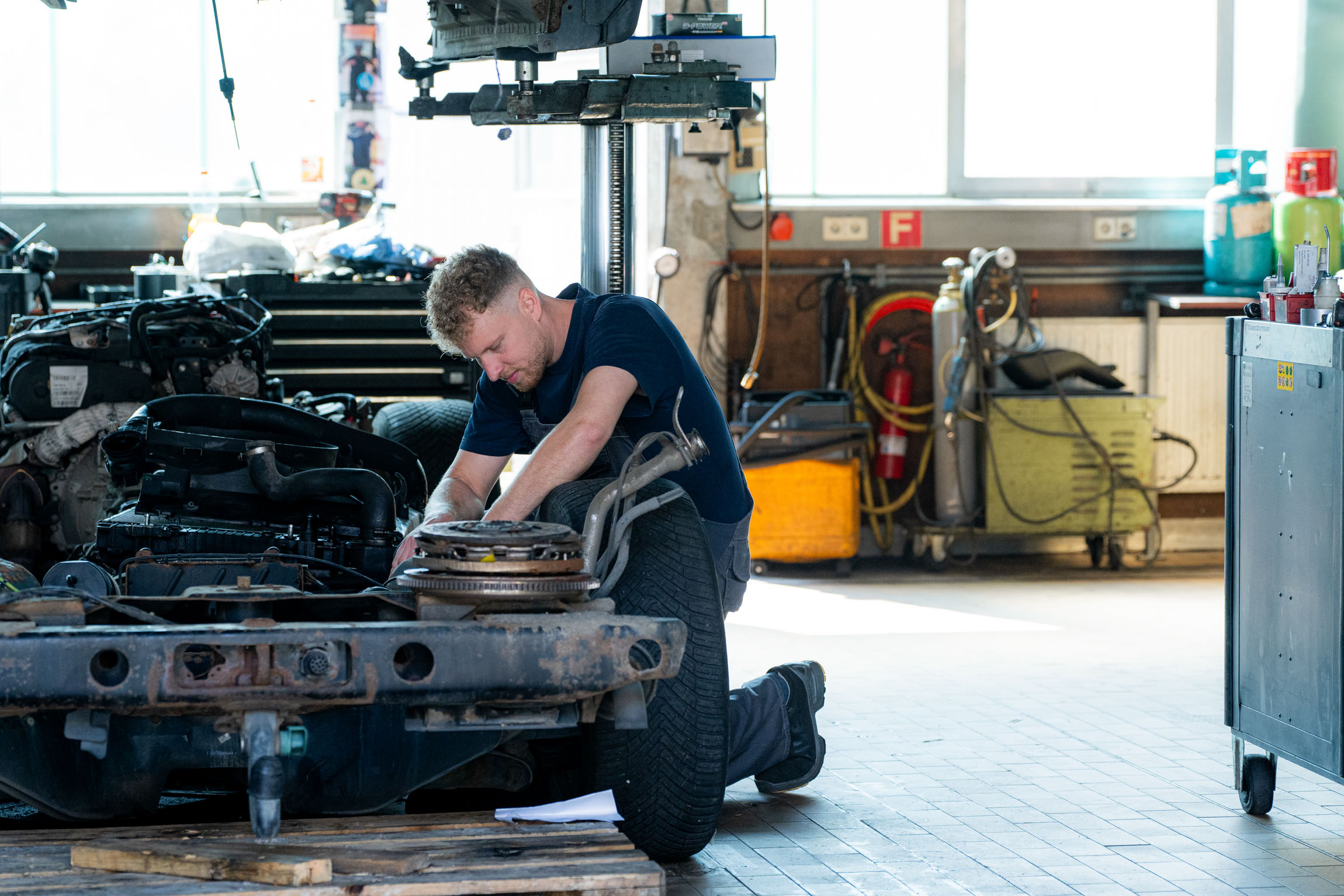 Ein Mann ist mit der Reparatur eines Fahrzeugs beschäftigt, um dessen Funktionalität und Sicherheit zu gewährleisten.