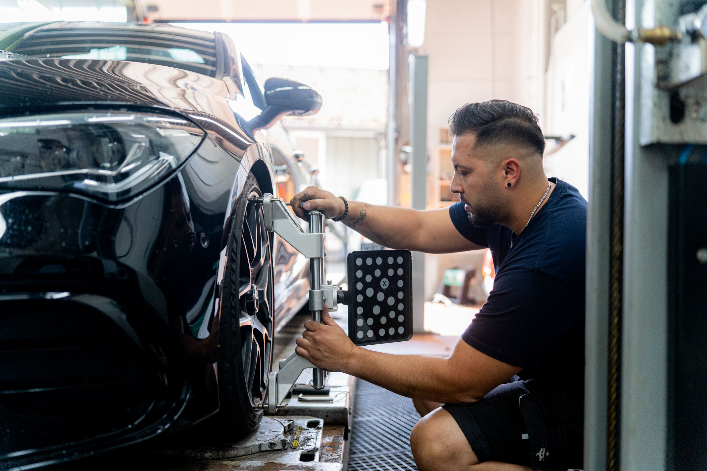 In einer Garage führt ein Mann Wartungsarbeiten an einem Auto durch, um dessen Funktionalität sicherzustellen.