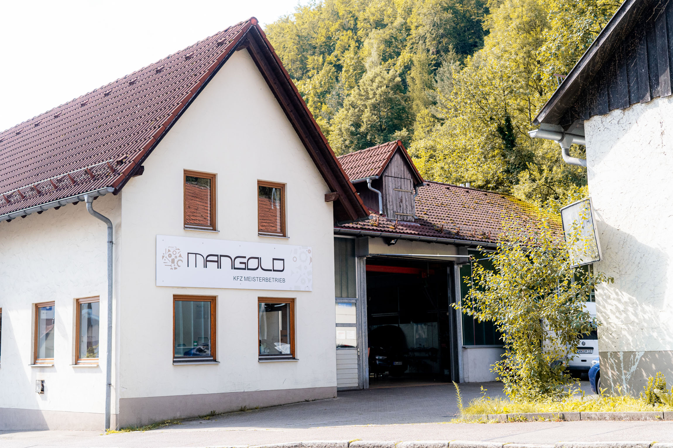 Ein Gebäude mit einem Schild, das den Kfz Meisterbetrieb Mangold anzeigt.